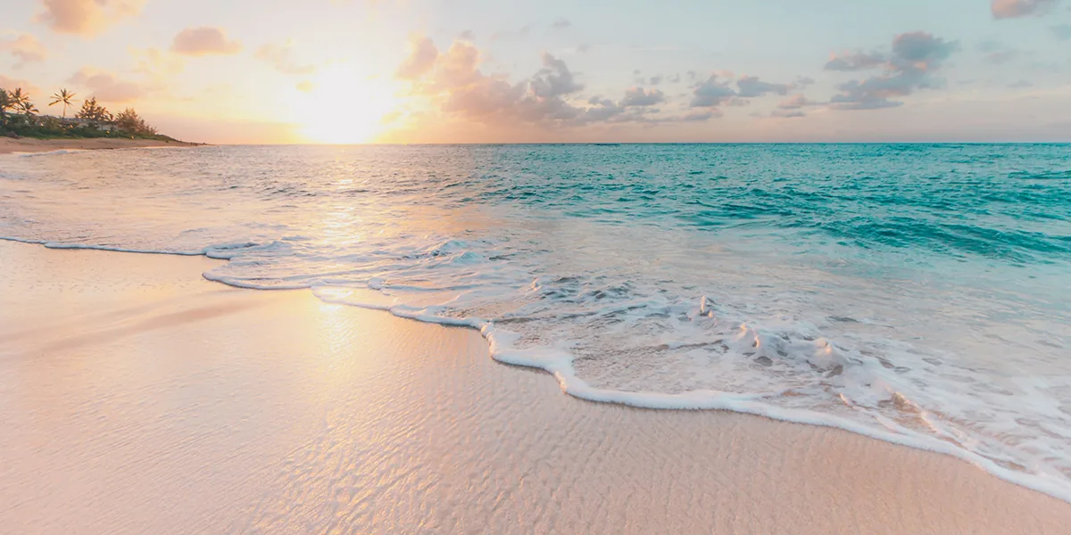 Gentle waves washing onto an empty beach at sunrise