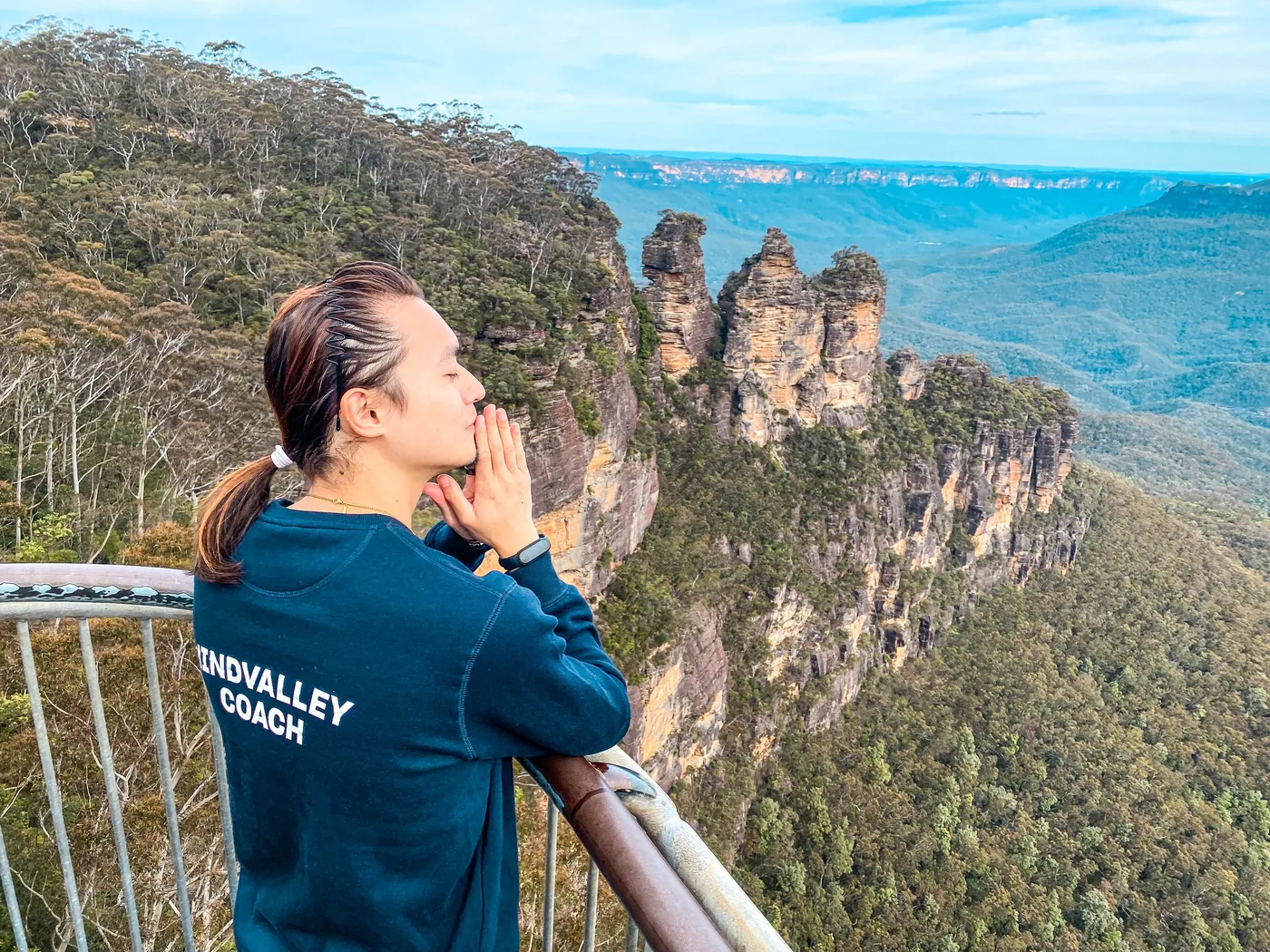 Freeman Fung in a Mindvalley Coach hoodie looking out at the Three Sisters rock formation in the Blue Mountains