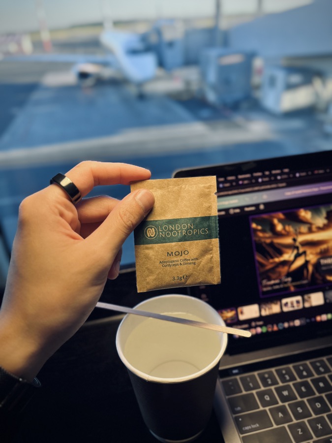 London Nootropics MOJO adaptogenic coffee sachet held up at an airport gate