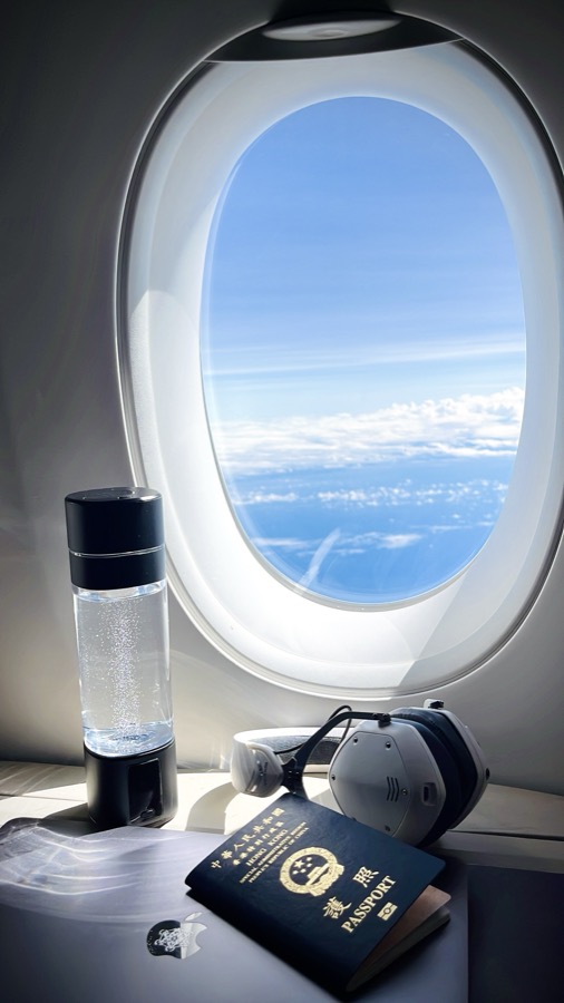 LumiVitae molecular hydrogen bottle beside an airplane window and Hong Kong passport